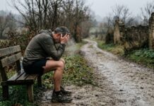 Runner maturo seduto su una panchina, momento di riflessione dopo un infortunio nella corsa